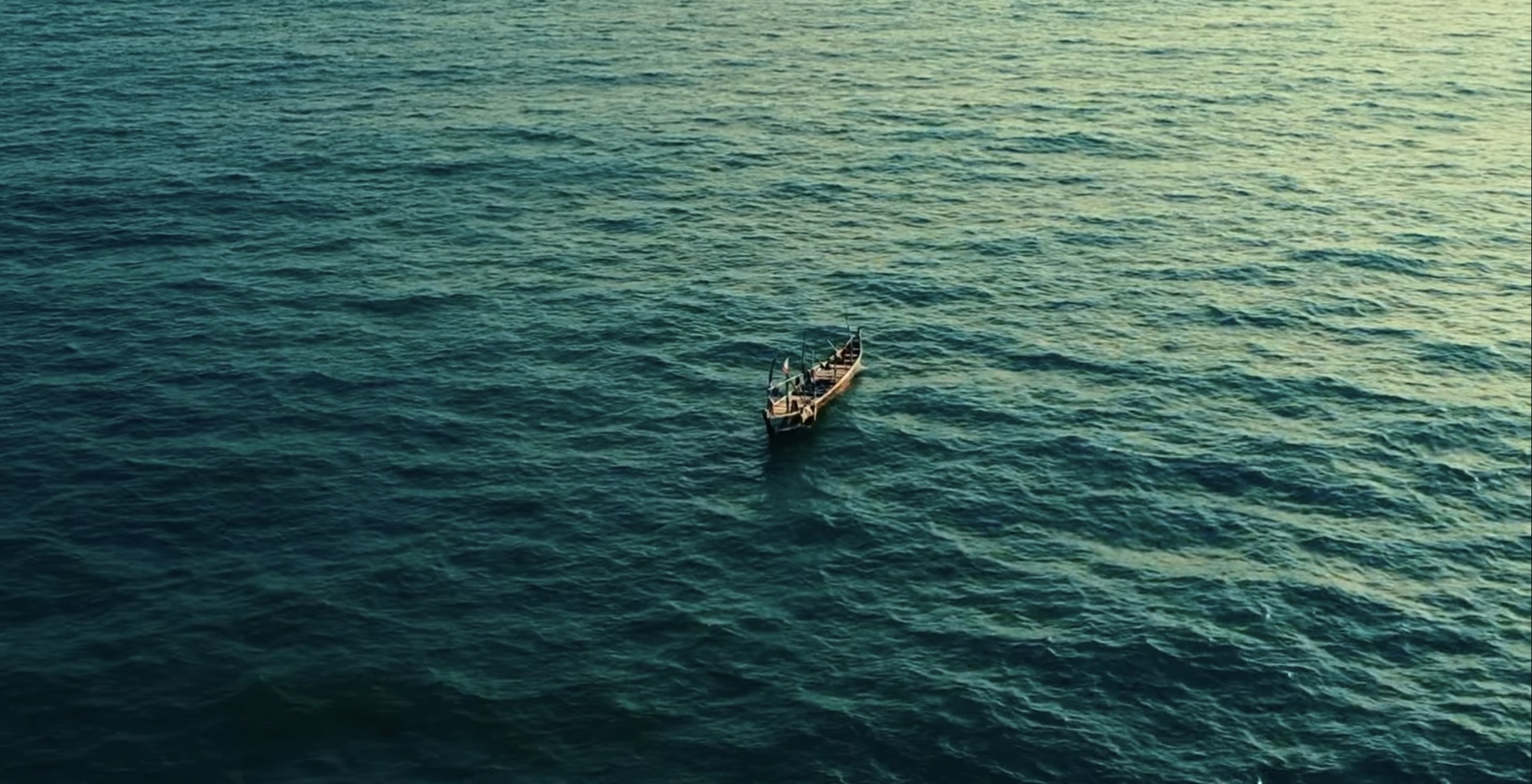 Une pirogue traditionnelle solitaire naviguant sur les eaux bleu azur de l'océan Atlantique au large des côtes, une scène paisible à admirer lors de votre voyage pour découvrir le Bénin